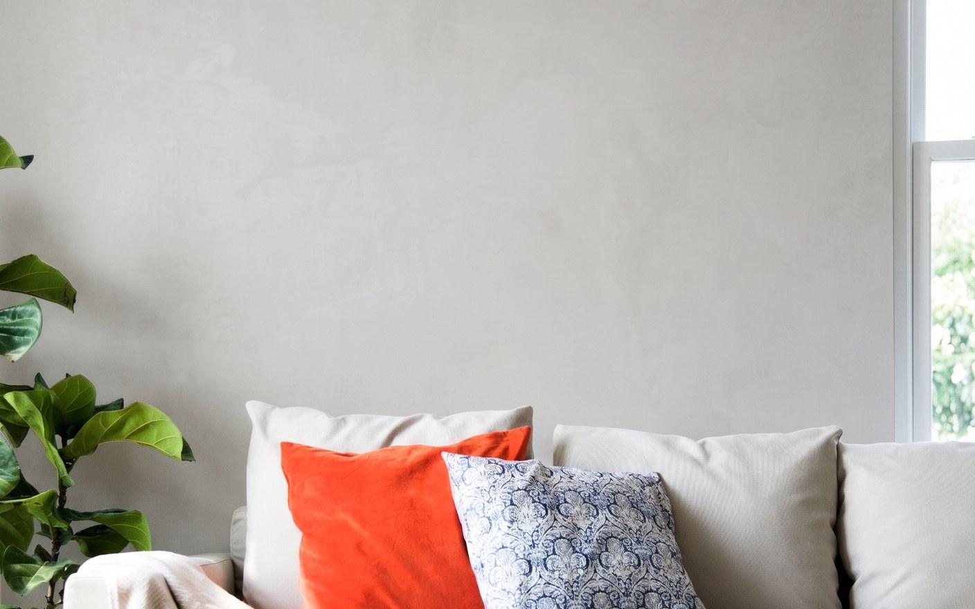 A living room with a bare plaster wall above the sofa