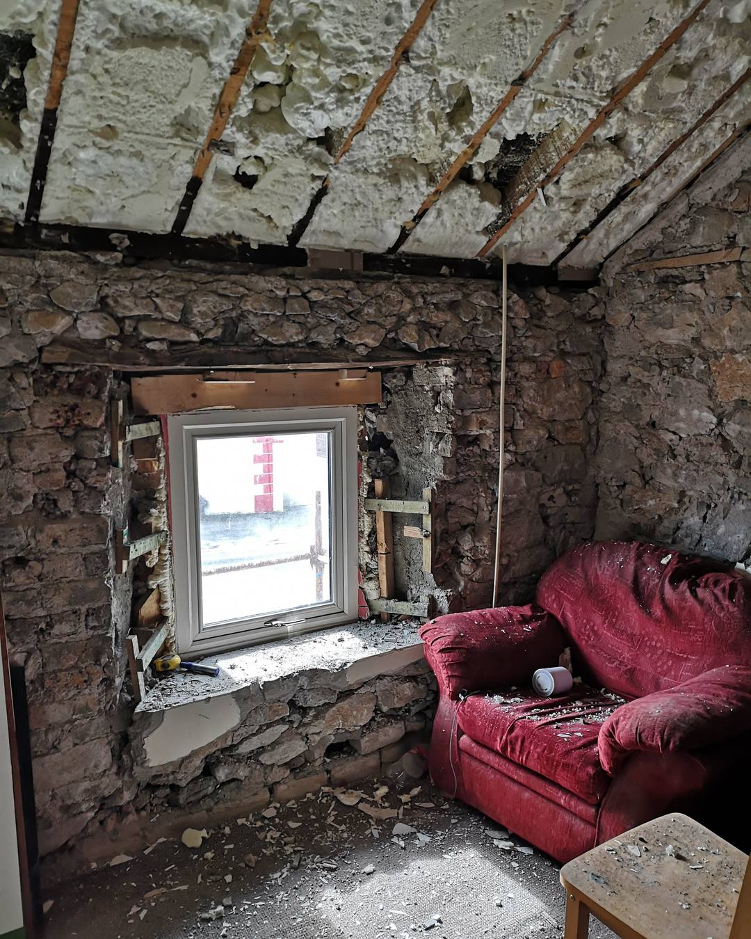 A room stripped back to bare stone, an old red armchair still in the corner.