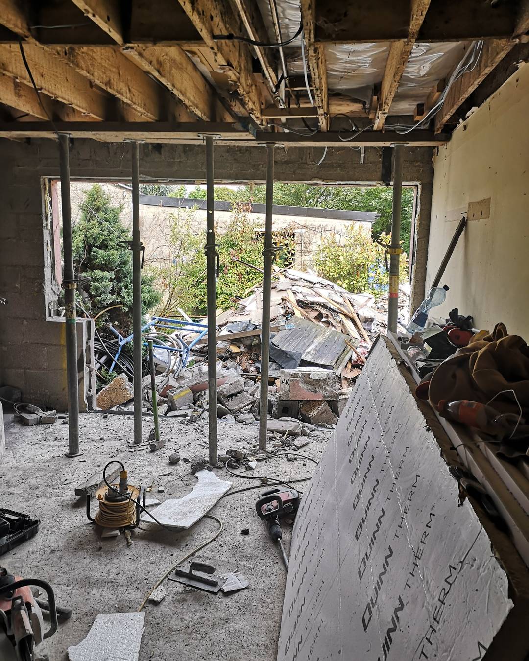 A room held up by acrow props, with a pile of rubble outside the opening.